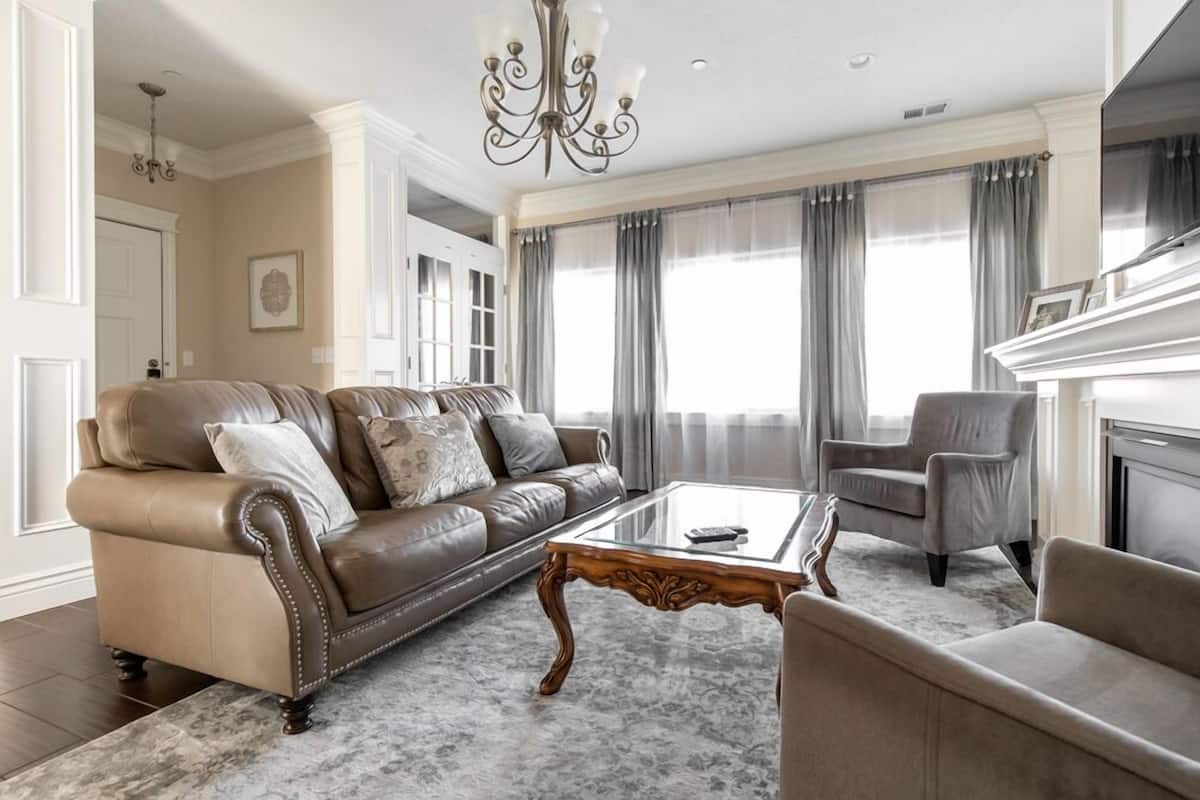 A living room with a leather sofa, a glass coffee table, and a fireplace.