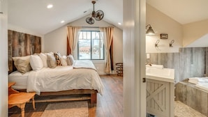 A bedroom with a large bed, a window with curtains, a ceiling fan, and a view of the outside. - Aspenwood Manor (Provo)