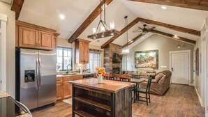 A spacious kitchen with wooden cabinets, a stainless steel refrigerator, and a central island. - Aspenwood Manor (Provo)