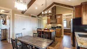 A spacious kitchen with wooden cabinets, a large island, and a dining area with a wooden table and chairs. - Aspenwood Manor (Provo)