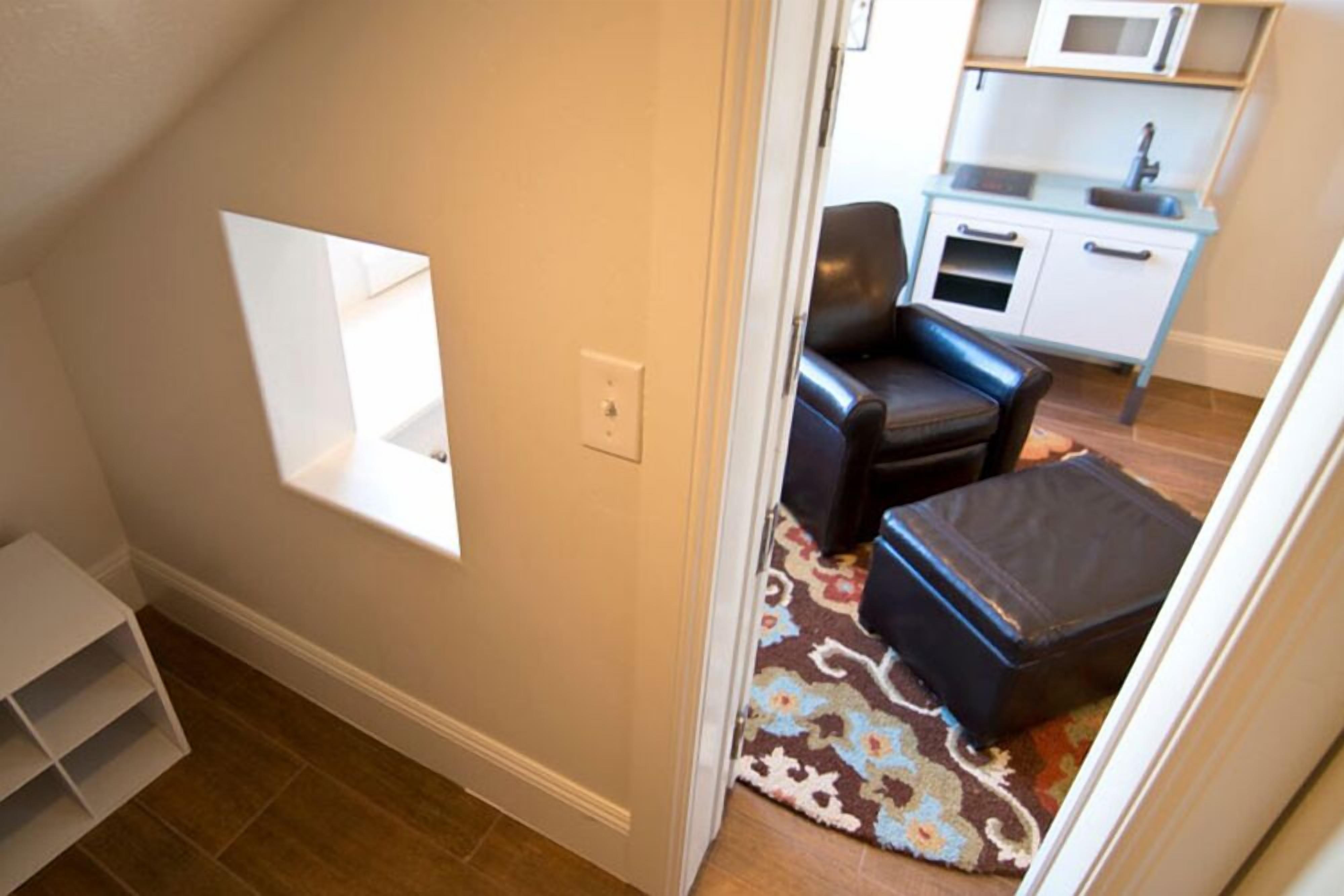 A compact living space with a kitchenette, a small seating area, and a built-in shelf.