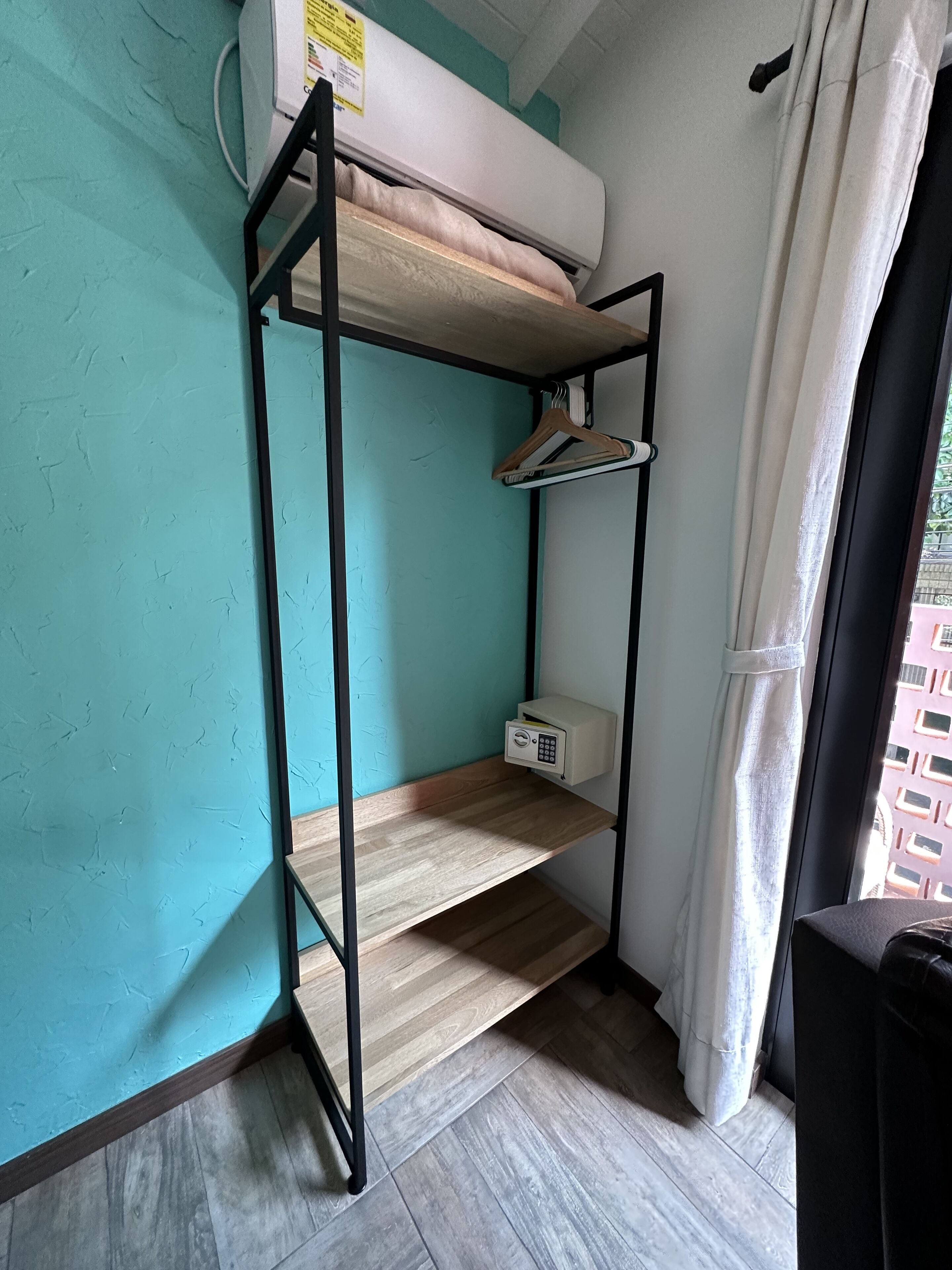Una cama litera con un panel de control, estante de madera y ventana con cortinas.
