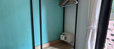 Una cama litera con un panel de control, estante de madera y ventana con cortinas.
