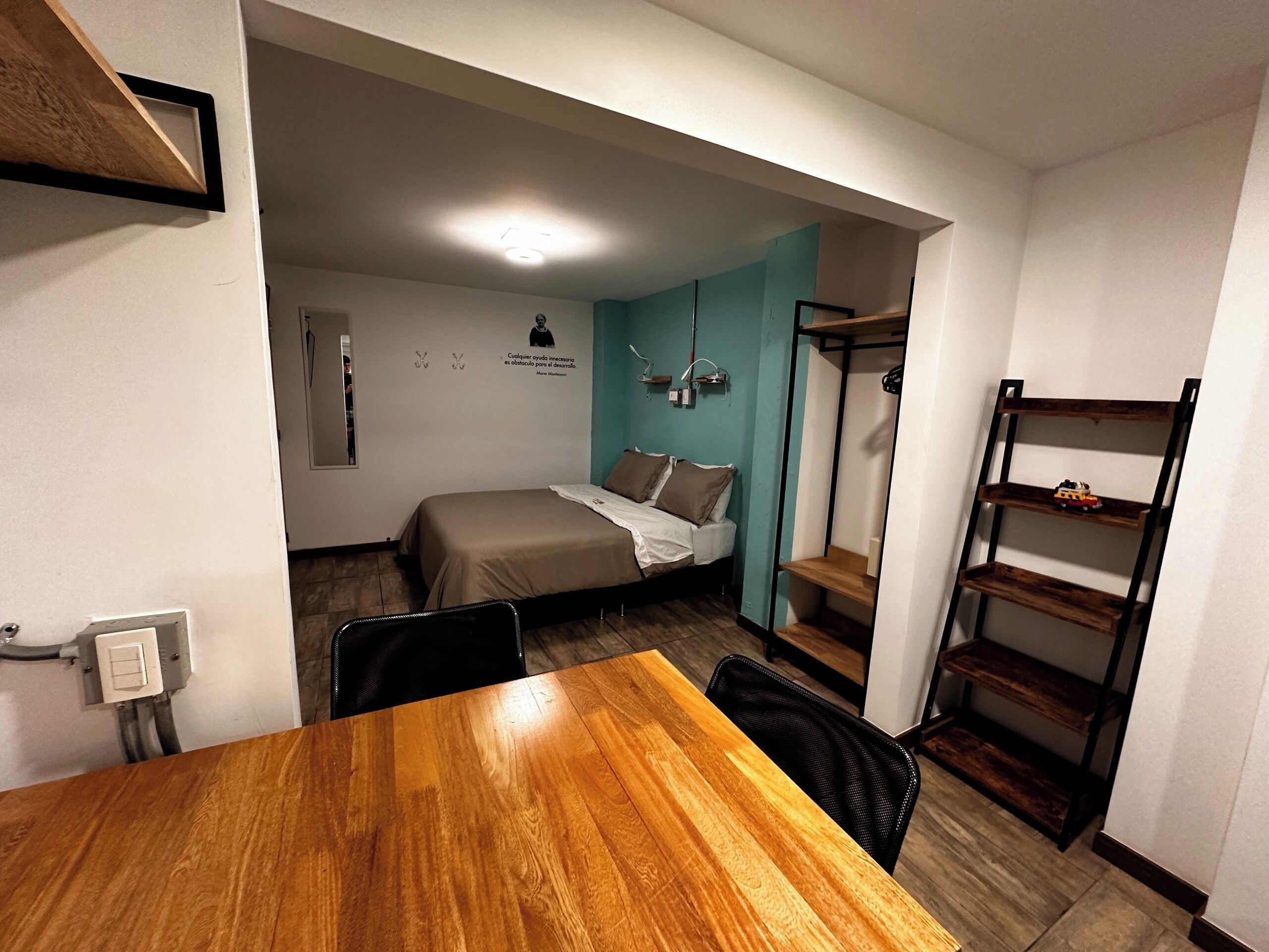 A compact room with a bed, a table, and a bunk bed.