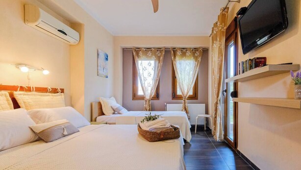 Ein Hotelzimmer mit zwei Betten, einem Fernseher, einem Fenster mit Vorhängen und einem Regal mit Büchern.