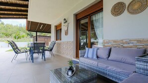 Eine Terrasse im Freien mit Esstisch, Stühlen, einer Couch und einem Couchtisch.