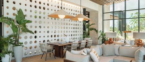 A modern living room with a white perforated wall, a wooden ceiling, and large windows.