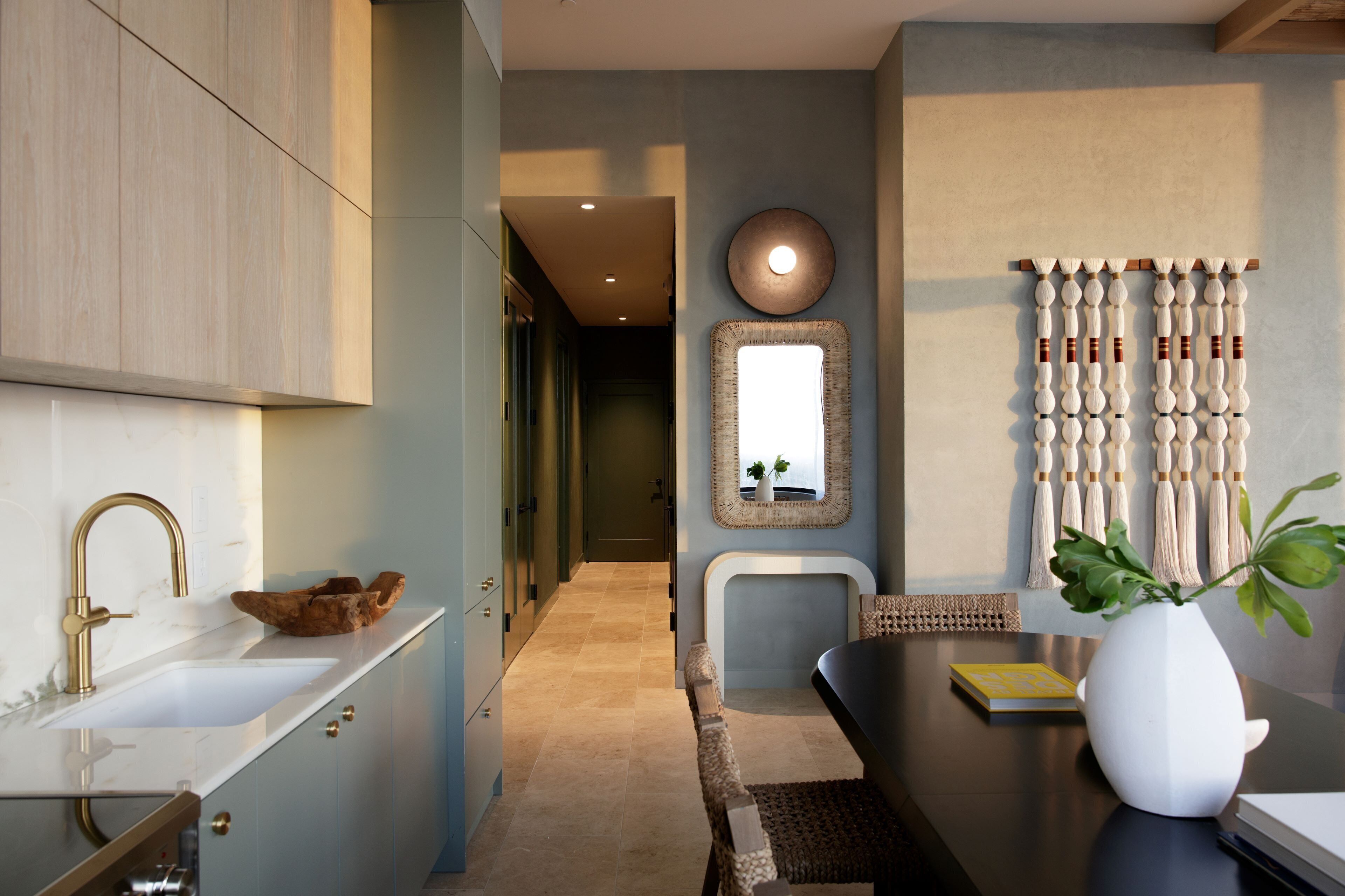 A modern kitchen with a built-in sink, a wooden bowl, and a vase with a plant.