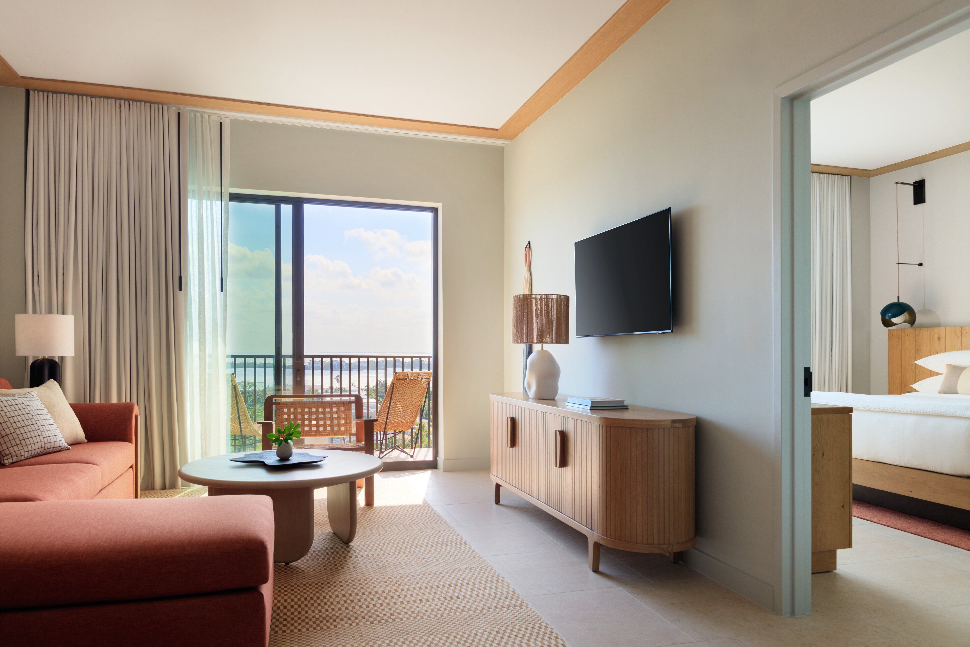 Een hotelkamer met een bank, een tafeltje, een televisie, een houten kast en een bed.