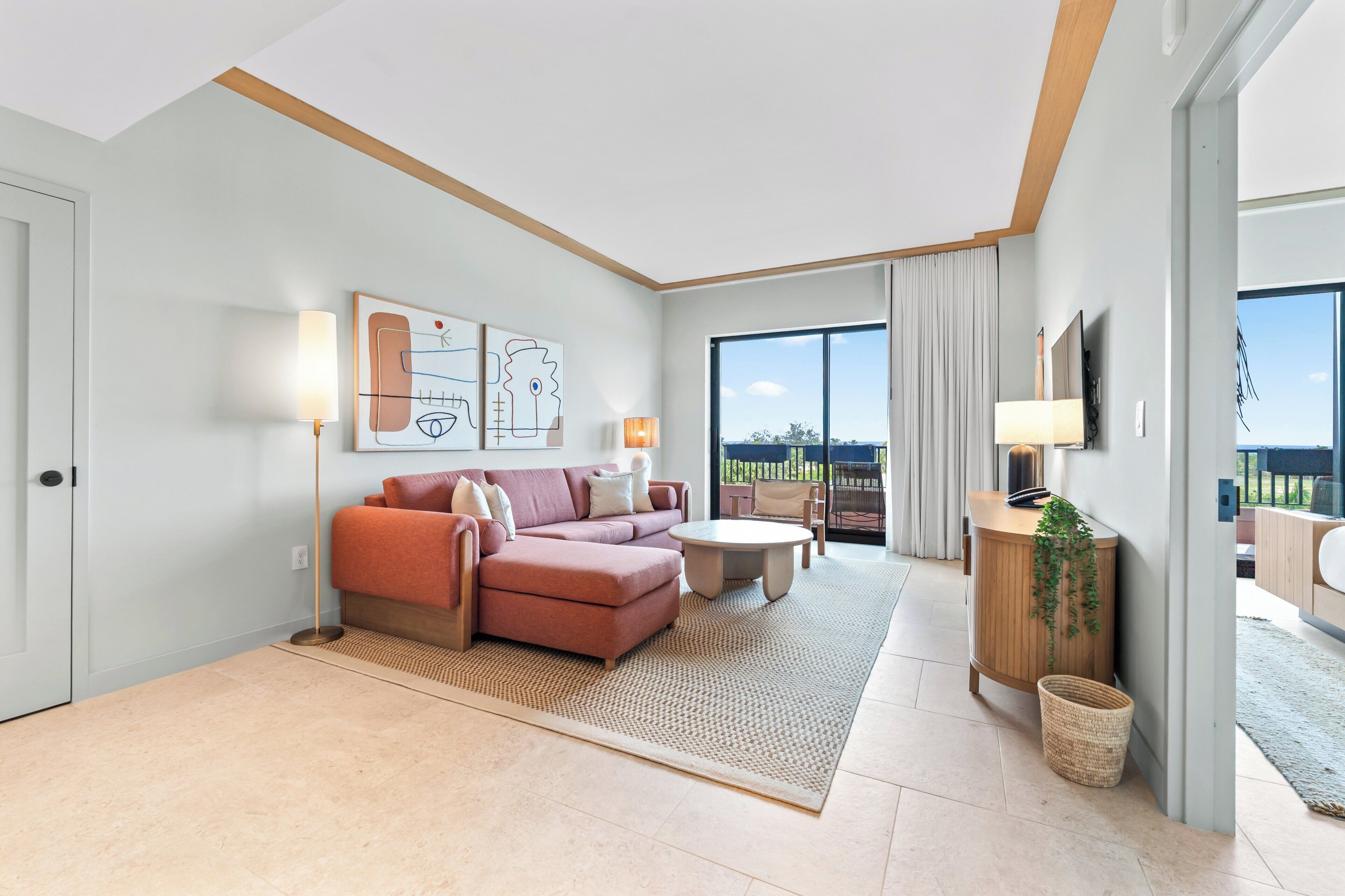 Habitación de hotel moderna con sofá, una mesita, televisión y balcón con vistas.