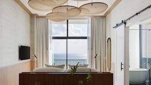 Un baño moderno con bañera, cabina de ducha de vidrio y un amplio ventanal con vista al océano.