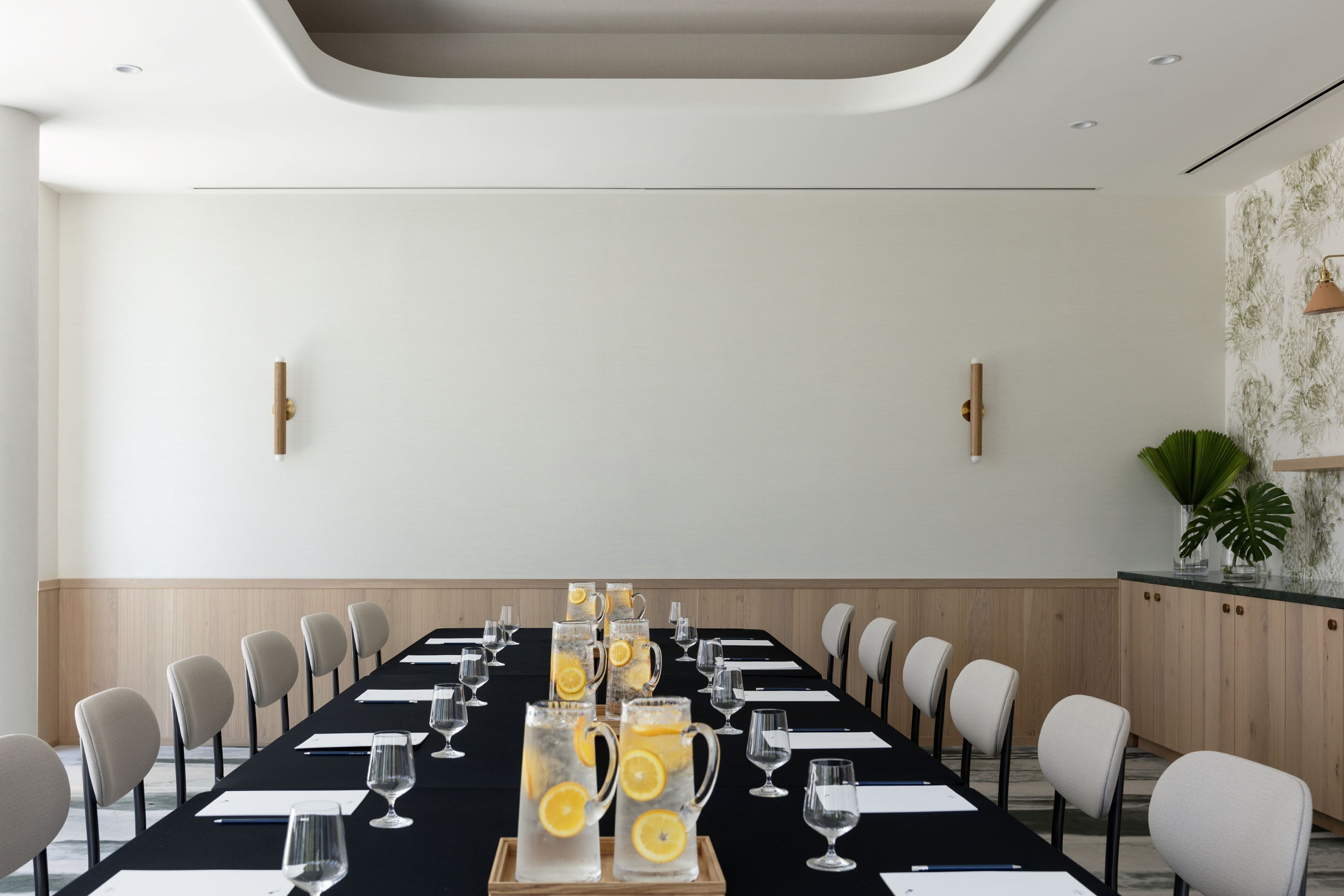 A conference room with a long table, chairs, and a pitcher of lemonade.