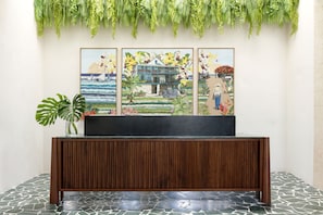 A reception area with a wooden console table, a large framed painting, and a potted plant.