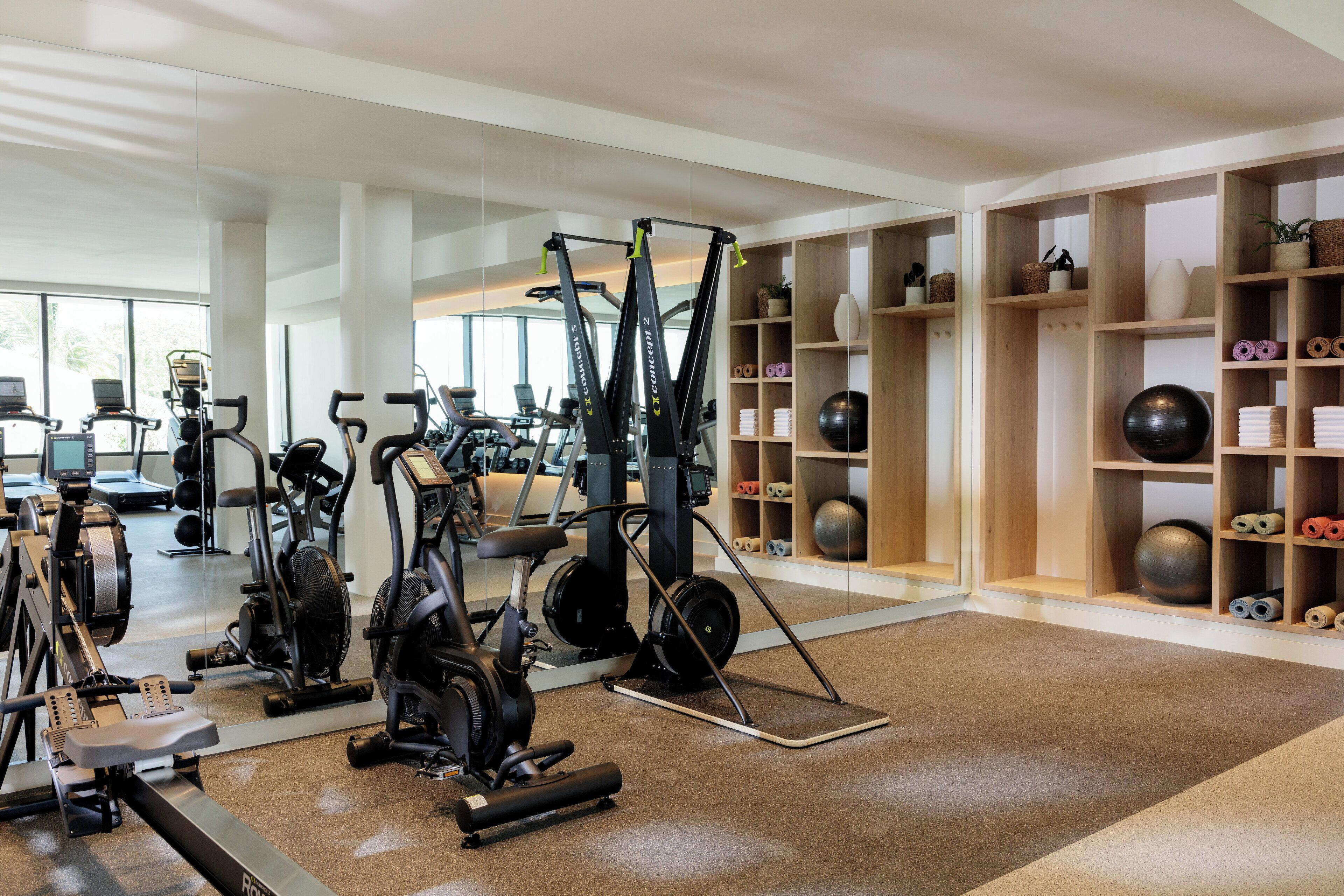 A gym with cardio machines, free weights, and exercise balls.