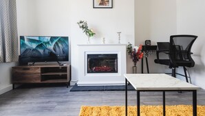 Un salon moderne doté d’un téléviseur à écran plat, d’une cheminée, d’une table à manger et d’un fauteuil de bureau noir.