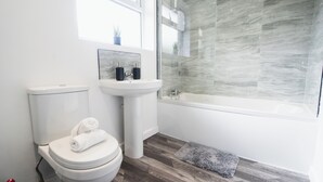 Une salle de bain moderne équipée de toilettes, d’un lavabo et d’une baignoire.