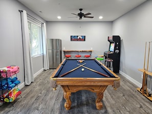 Une table de billard, un ventilateur de plafond, un réfrigérateur et une pancarte sur laquelle on peut lire : « SALLE DE DÉTENTE ».