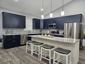 A modern kitchen with dark cabinets, a stainless steel refrigerator, a microwave, and a granite countertop.