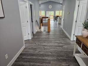 A hallway with a wooden floor leading to a dining area with a view of trees. - Heart of Branson Retreat / Hot Tub / Pool Table / Game Room / Fire Pit / Lvl2 EV (Branson)