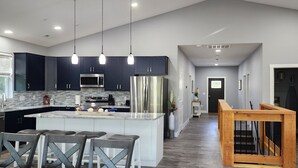Une cuisine moderne avec des meubles de couleur sombre, des appareils en acier inoxydable et un îlot central doté de tabourets de bar.