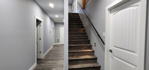 Un couloir avec un escalier en bois menant à une porte.