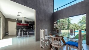 Una cocina moderna con una mesa de comedor de vidrio y sillas, vistas al exterior y un ventanal grande.