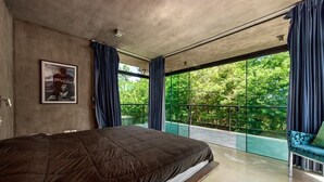 Un dormitorio moderno con una cama grande, un cartel en la pared y un balcón con vistas a zonas verdes.