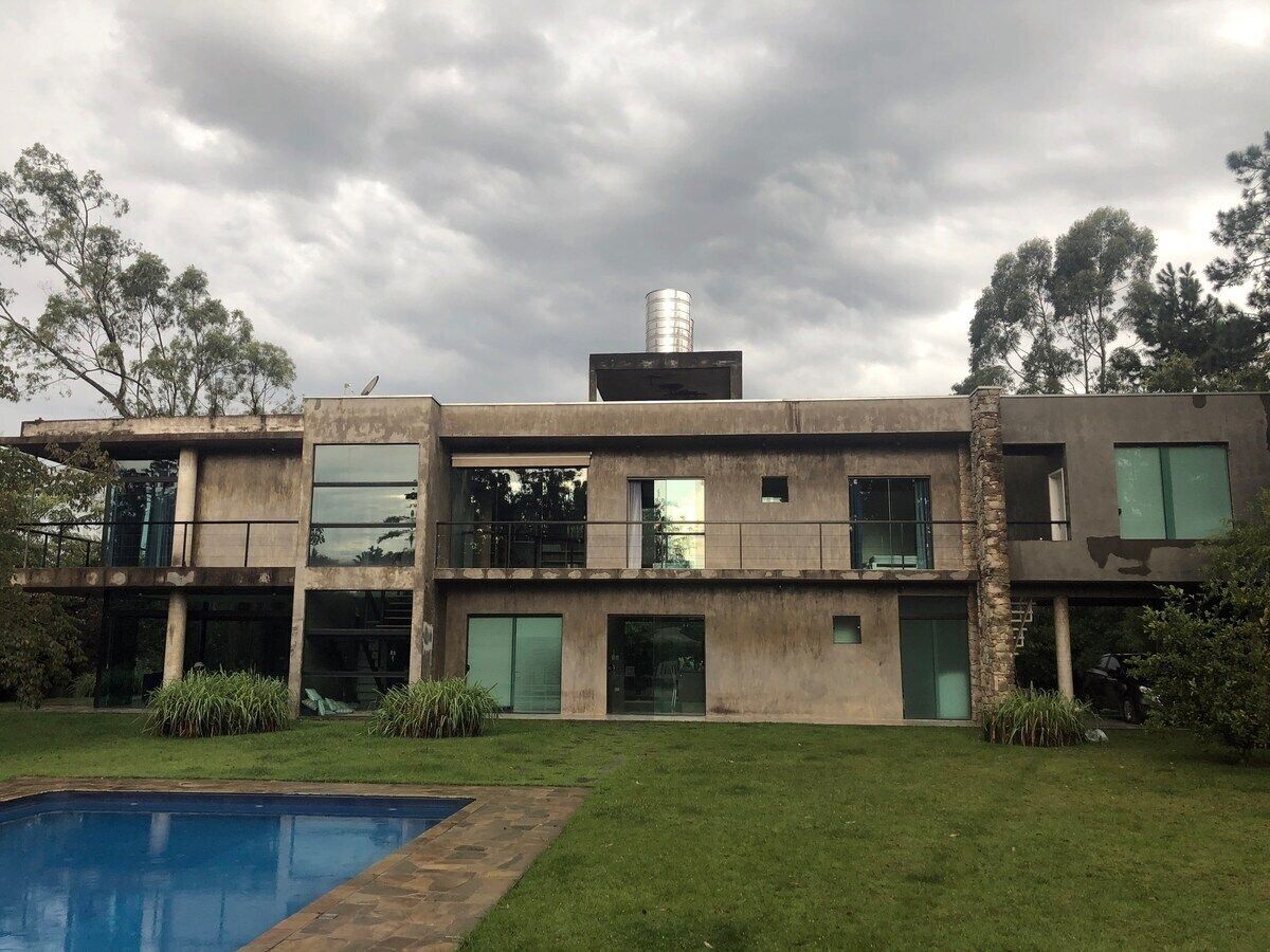A modern two-story house with a swimming pool, large windows, and a chimney.