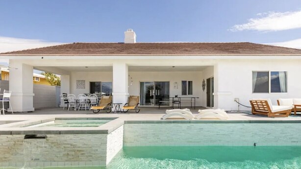 A modern house with a swimming pool, outdoor seating, and a covered patio.