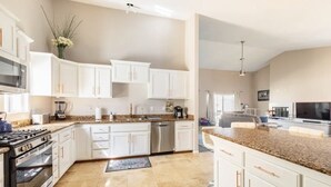 A spacious kitchen with white cabinets, granite countertops, and stainless steel appliances.