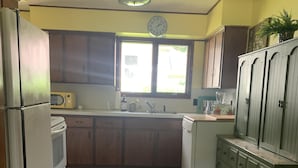 Una cocina compacta con armarios de madera, un microondas, un fregadero y un reloj en la pared.