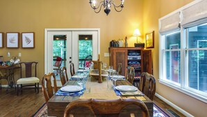 A dining room with a long wooden table set for six, surrounded by wooden chairs. There is a chandelier above the table, and a window on the right side. - Dog-Friendly Dahlonega Home w/ Private Fire Pit! (Dahlonega)