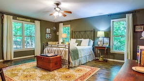 A bedroom with a bed, a wooden dresser, a nightstand, a desk, and a large window. - Dog-Friendly Dahlonega Home w/ Private Fire Pit! (Dahlonega)