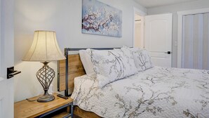 Un dormitorio con una cama, una mesita de noche con una lámpara y un cuadro en la pared.