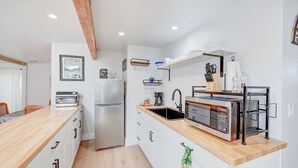 Una cocina compacta con encimera de madera, horno empotrado, microondas y fregadero.