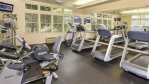 Un gimnasio con cintas de correr, bicicletas estáticas y máquinas de pesas.