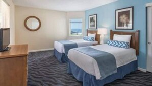 A hotel room with two beds, a TV, a desk, and a view of the ocean. - Luxury 2BR Condo for Music Fests (Indio)