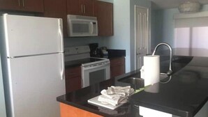 A kitchen with a refrigerator, microwave, stove, and sink. - Luxurious 1BR Condo for Coachella Week 2 (Indio)