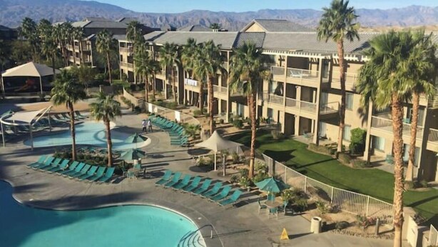 A resort with a swimming pool, lounge chairs, and palm trees. - Luxurious 1BR Condo for Coachella Week 2 (Indio)