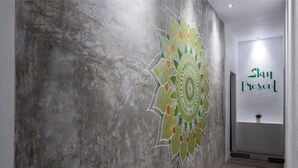 Un couloir orné d’une grande fresque murale représentant un mandala aux couleurs vives, et sur lequel on peut lire l’inscription : « Slau est là ».