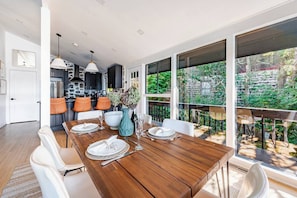 Una cocina moderna con armarios oscuros, una pared de acento de piedra y una zona de comedor con mesa de madera para cuatro.