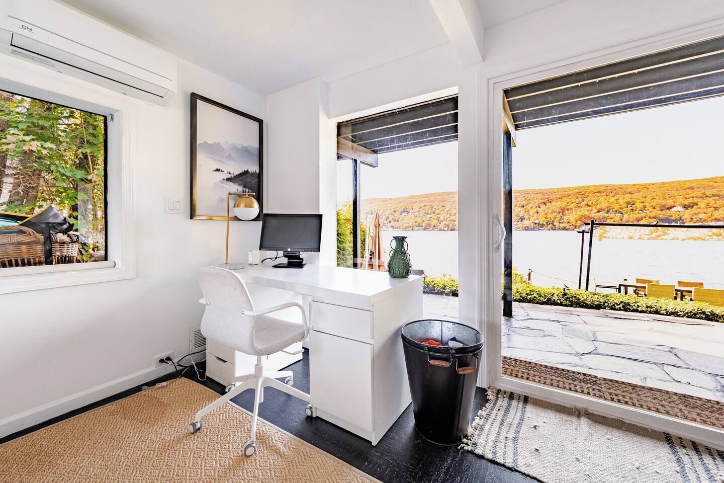 Um espaço de escritório moderno com escrivaninha, cadeira, computador e uma grande janela com vista para uma paisagem deslumbrante.