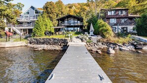 Un hotel a orillas del río con muelle, muros de piedra y un puente.