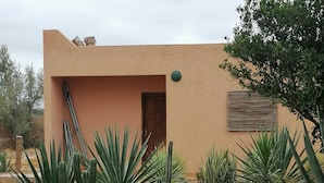 Ein Gebäude mit einer beige farbenen Fassade, umgeben von einem Kiesgarten mit verschiedenen Kakteen und Sukkulenten.