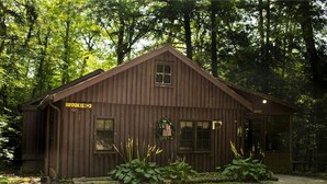 Eine rustikale Holzhütte mit der Aufschrift „BROOKIE #3“, umgeben von dichtem Wald.