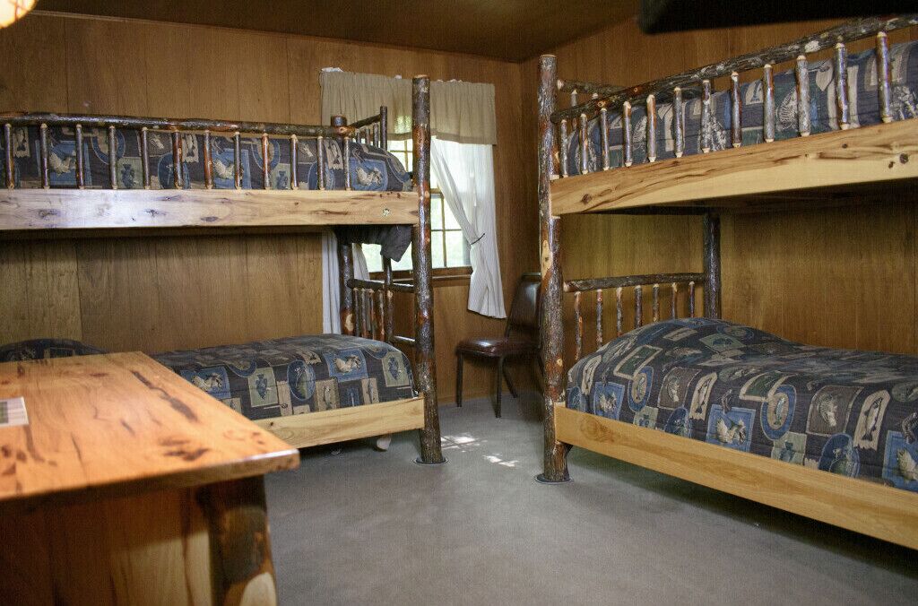 A bunk bed room with a wooden table and a chair.