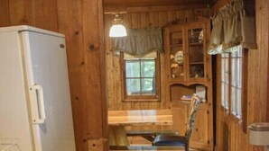 Ein Interieur einer Holzhütte mit Küchenbereich, einem Esstisch und einem Fenster.