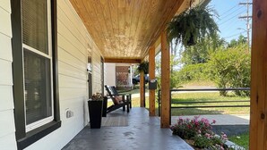 Un porche cubierto con piso de concreto, techo de madera y un felpudo en la entrada.