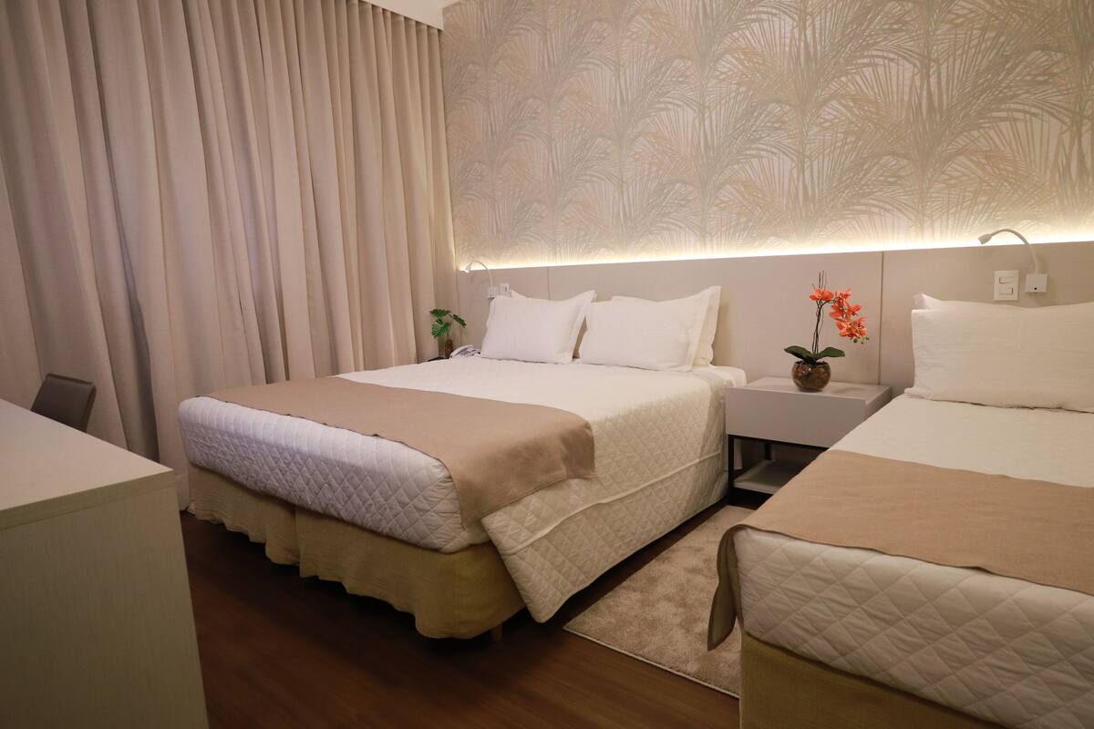 Een hotelkamer met een bed, nachtkastjes, een lamp en een gordijn.