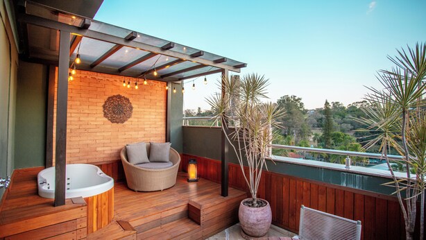 A wooden deck with a hot tub, wicker furniture, and potted plants. - LS Villas Tranquillità (Aguas de Sao Pedro)